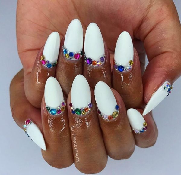 Matte white nails are given a op of colour thanks to clusters of glittering jewels by Jema Baynes