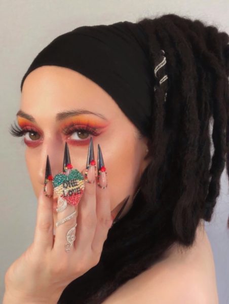 Debbie Marangos
"This is a first for me, as I have never entered a competition being the model. Although nails are my absolute passion, I didn't want to go with the obvious, so I did something to reflect my way of life, and that is as a Rastafarian woman. I have incorporated the traditional Rasta colours in the nail design, red, gold, green & black, and I created the One Love heart emblem, out of Swarovski crystals & black caviar beads over a base of builder gel. I wanted my hair to be in the photo, as this is who I am, my hair is my strength, and I wanted the nails in fierce stiletto form, to represent the lionesses claws. My business name, Lioness Paws, is a great reflection of who I am, a nail artist, a mother to 13 children, and a powerful & strong woman."