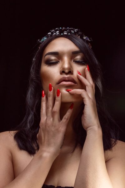 Eloise Nom Chong
"The darkness of the photo represents the obstacles and hardships we encounter in life, the crown represents a reminder of who I am able/meant to be a placement in my life, the ability to rise above and conquer trials and tribulations with steadfastness and unwavering strength. The positioning of my head, facing upwards represents, keeping my head up through all life's issues, good and bad the light shining on me is my faith and reminder that there are always ways to rise out of any situation. The red nails are my assertiveness, boldness and my extroverted personality. I chose the color red because it puts an emphasis on the nails which are my career, its my grounding and foundation of why I am able to be where I am today."