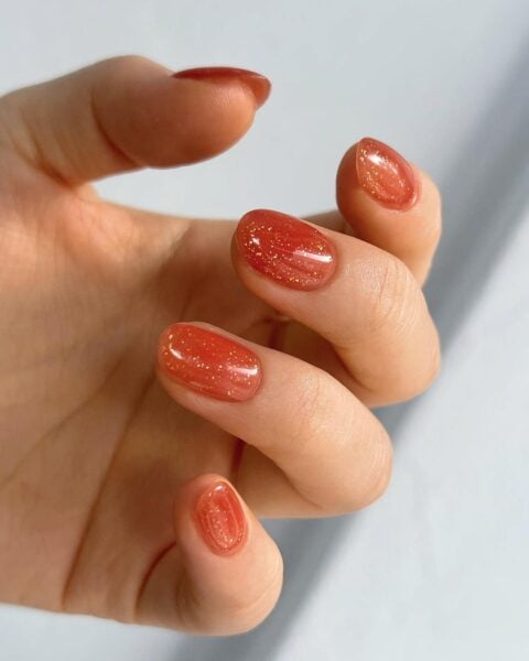 @dazznail of Haus Dazz adds gold glitter to a warm orange jelly hue.