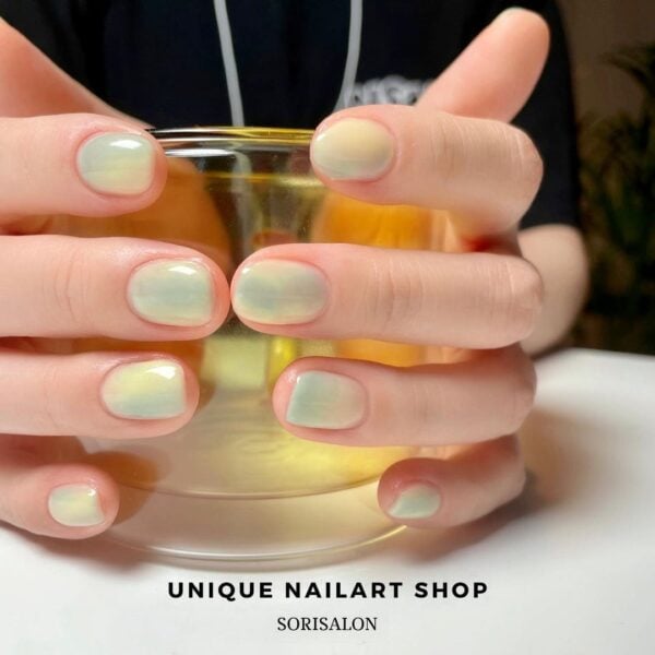 @sorisalon creates a green and yellow marble-effect on nails with a syrup finish.