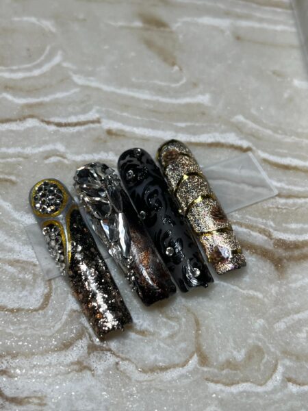 Elegant nail art designs with metallic, black, and glitter finishes for nail professionals and salons.